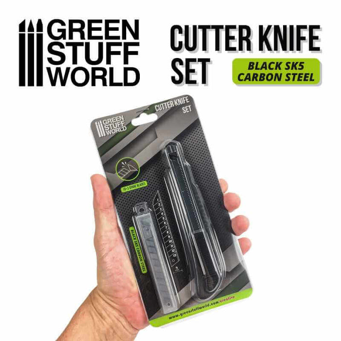Hand holding a package of black hobby cutter knife 10x spoare blades. Black SK5 carbon steel.